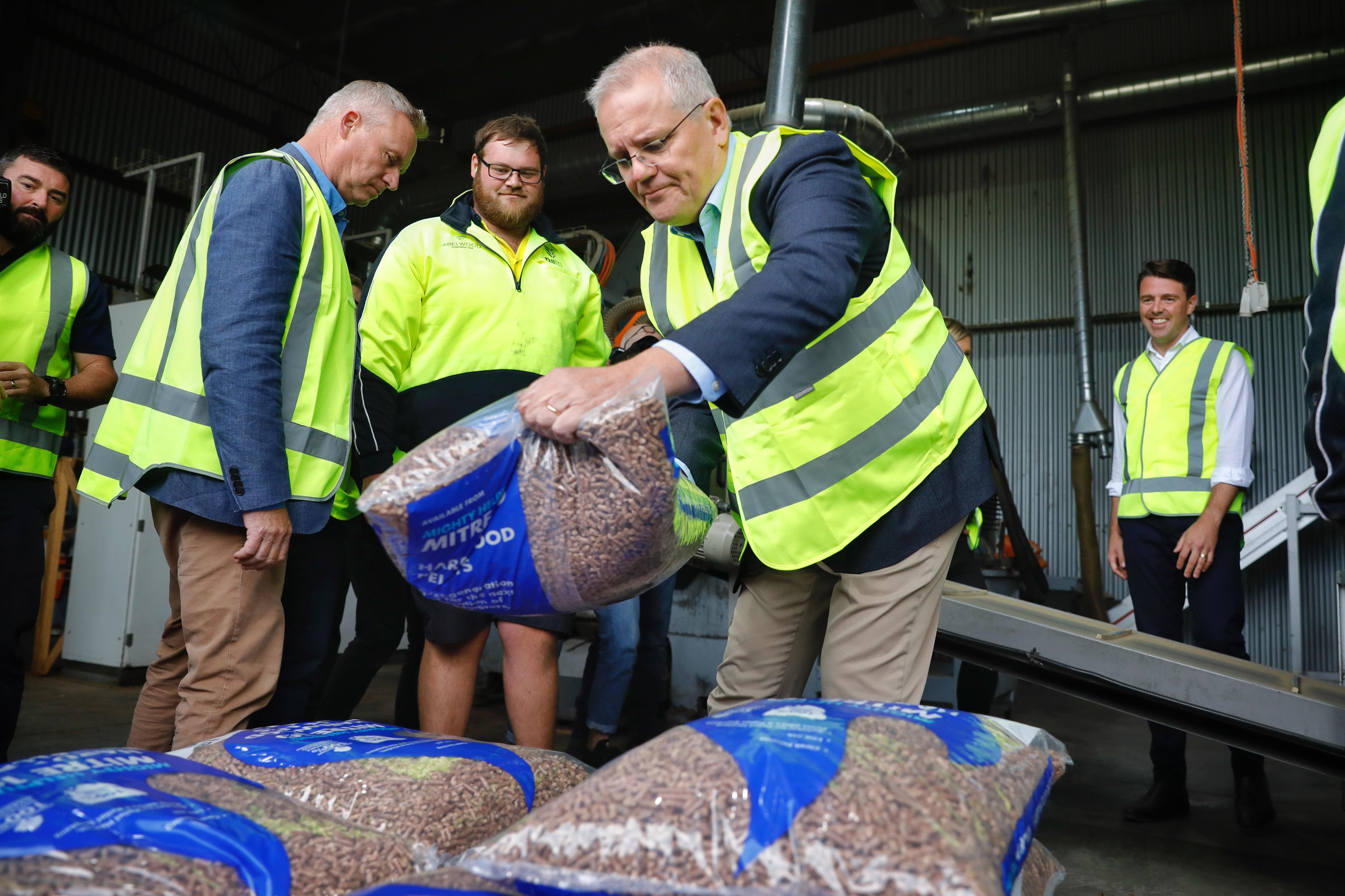 Scott Morrison carries a sack of pellets while wearing yellow high-vis.